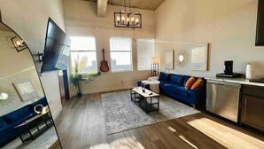 A modern living room with a blue sofa, a coffee table, a TV, and a guitar. - New York Style Home 10 Minutes To SNA Disneyland (Santa Ana)