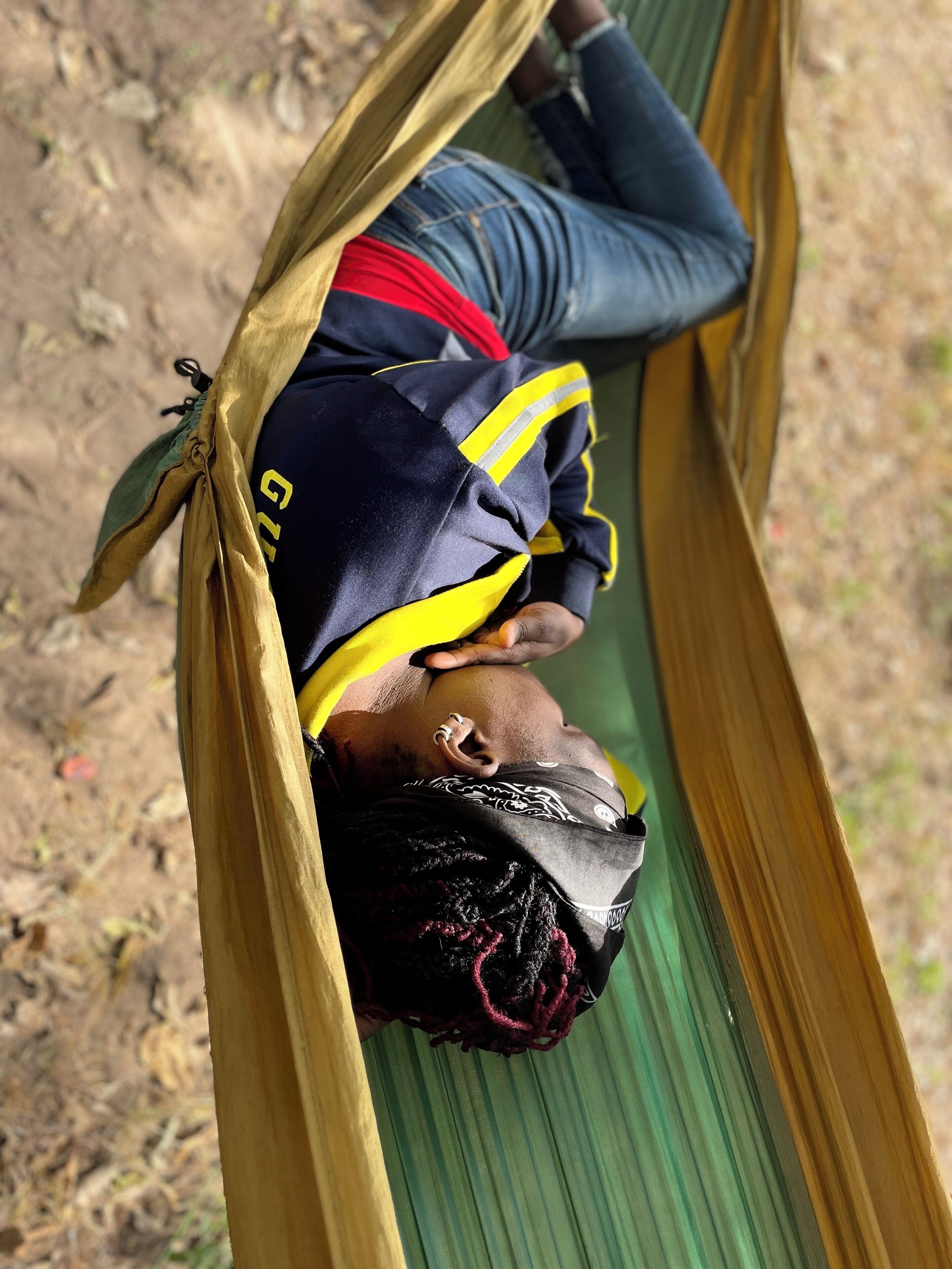 A person lying in a hammock outdoors.
