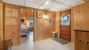 Un intérieur en bois comprenant un lit, une petite table et une porte ornée d’une guirlande.
