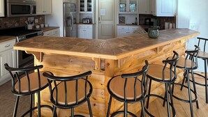 A kitchen with a large island, bar stools, white cabinets, and wooden beams. - Beautiful 3 bed, 3.5 bath at Cedar Stone in Eminence MO. Sleeps up to 16 guests. (Eminence)