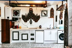 A kitchen with white cabinets, a granite countertop, a washing machine, and decorative wall art.