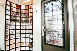 Una habitación con una puerta de vidrio curva y una ventana de vidrio rectangular con detalles de metalería.