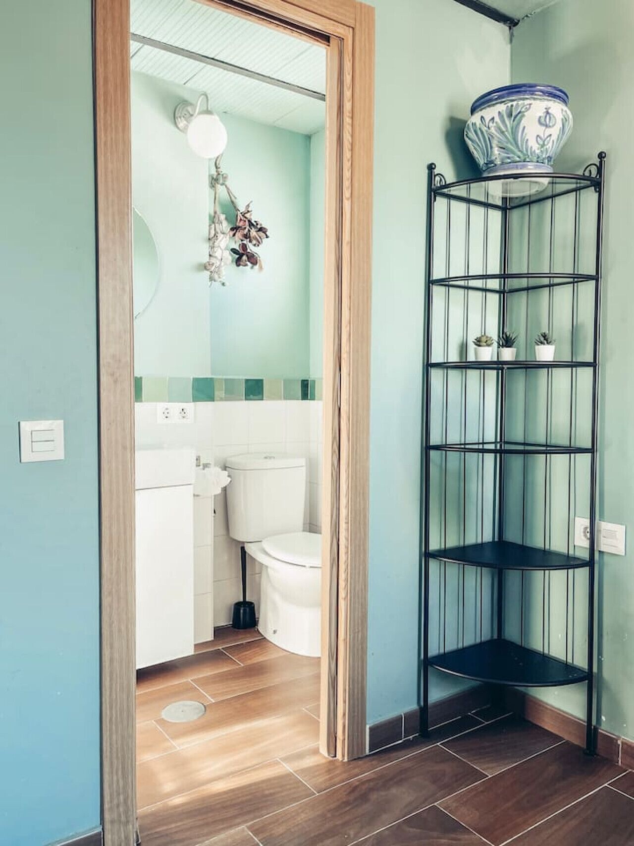 Et hjørne badeværelse med toilet, vask og hjørnehylde.