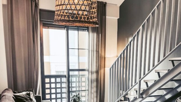 Ein moderner Essbereich mit einem runden Tisch, gedeckt für vier Personen, einer Treppe und Blick auf die Stadt durch große Fenster.