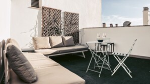 Eine Dachterrasse mit einer Couch, Sesseln und einem Tisch.