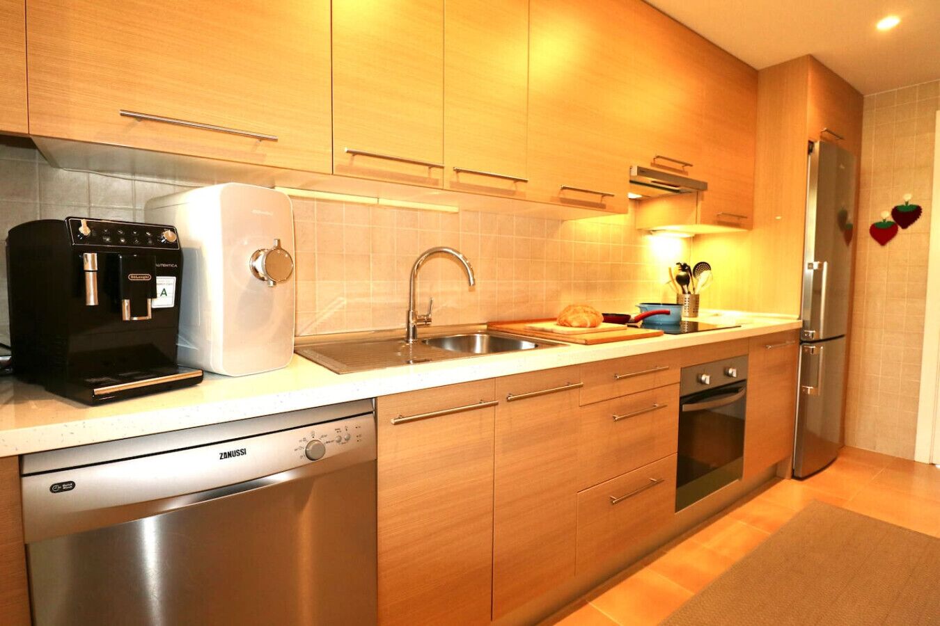 A modern kitchen with stainless steel appliances, wooden cabinets, and a built-in dishwasher.