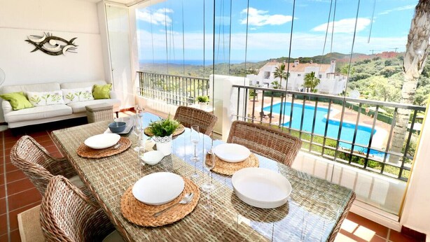 A dining area with a table set for four, overlooking a pool and hills. - Mirador Marbella | Pool | Golf | Gym | Sauna (Ojén)