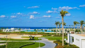 A resort with a pool, palm trees, and a clear blue sky. - Magnificent 1-BR Sea view  Address Beach Marassi (El Alamein)