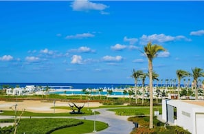 A resort with a pool, palm trees, and a clear blue sky. - Magnificent 1-BR Sea view  Address Beach Marassi (El Alamein)