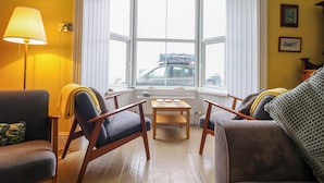 Ein gemütliches Wohnzimmer mit Erkerfenster, Holzmöbeln und einer Lampe.