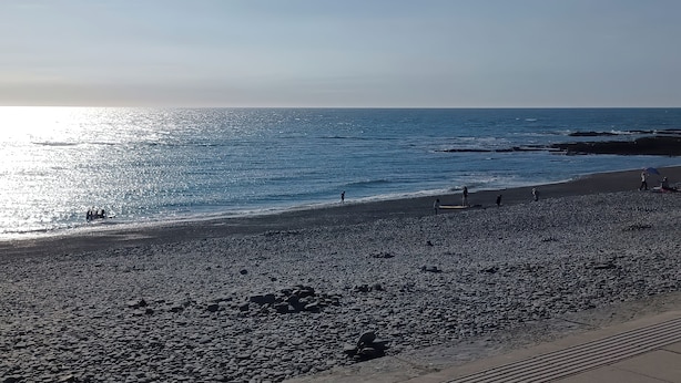 Ein Strand mit Kieselsteinen und freiem Blick auf das Meer.