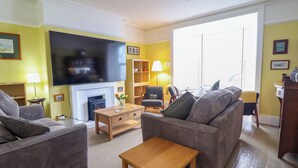 Ein Wohnzimmer mit Kamin, einer Couch und einem Fernseher.