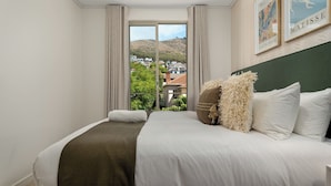 Un dormitorio con una cama grande, vistas a una ladera y dos obras de arte enmarcadas en la pared.
