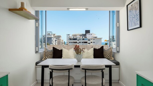 A modern kitchen with a dining area, large windows, and a view of the cityscape. - Heart of Seapoint Hideaway (Cape Town)
