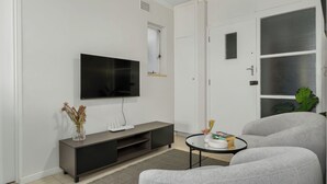 A modern living room with a flat-screen TV, grey sofa, and a small coffee table. - Heart of Seapoint Hideaway (Cape Town)