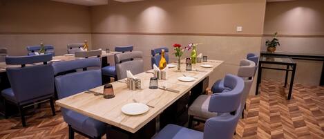 Un salón de conferencias con varias mesas y sillas, equipado con platos, cubiertos y elementos decorativos.