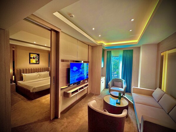 A modern hotel room with a bed, a TV, a sofa, and a coffee table. - ASTER GRAND BY ZENQ SAKET (New Delhi)