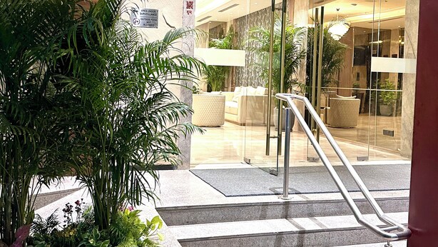 A hotel lobby with a glass entrance, a staircase, and indoor plants. - ASTER GRAND BY ZENQ SAKET (New Delhi)