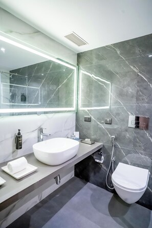 A modern bathroom with a white sink, a large mirror, and a toilet. - ASTER GRAND BY ZENQ SAKET (New Delhi)