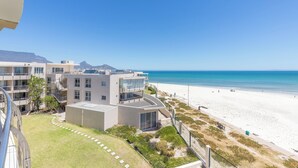 A modern hotel with a beach view, featuring a spacious courtyard and multiple balconies.