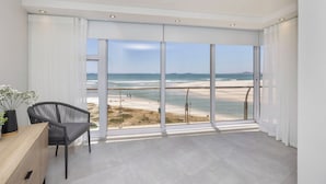 A spacious room with a large sliding glass door leading to a beach view.