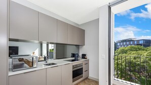 A modern kitchen with a large window, a built-in oven, and a view of the city.
