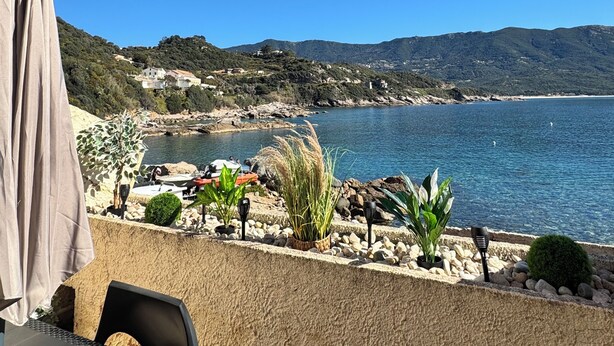 Une vue sur la côte, avec une table et des chaises, une plage et des montagnes en arrière-plan.