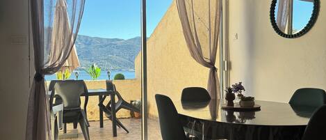A room with a dining table, chairs, a mirror, and a view of the outdoors.