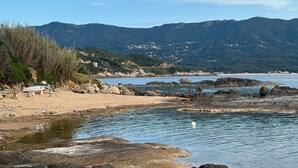 Un paysage côtier caractérisé par une eau limpide, une côte rocheuse et des montagnes lointaines.