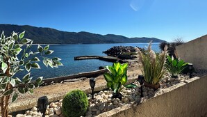 Un paysage côtier avec une rive rocheuse, une petite construction et diverses plantes.