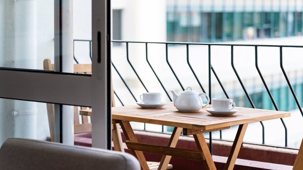 A balcony with a wooden table and chairs, a white teapot, and two white cups. - GuestReady - Wake Up to the Heartbeat of Madeira (Funchal)