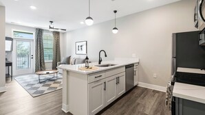 A modern kitchen with white cabinets, a black faucet, and a stainless steel refrigerator.