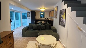 A modern living room with a green sofa, a round coffee table, and a staircase.