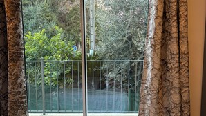 A room with a large sliding glass door leading to a balcony with a green fence.