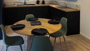 A modern kitchen with a round dining table, green chairs, and a chandelier.