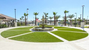 A well-maintained public square with a central fountain, surrounded by neatly trimmed grass and palm trees. - No Stairs 2BR Apartment at Champions Gate (Davenport)