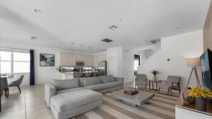 Ein modernes Wohnzimmer mit einer Eckcouch, einem Couchtisch und einem Essbereich mit Tisch und Stühlen.