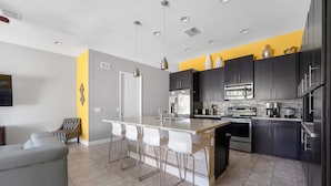 Una cocina moderna con una isla central, muebles oscuros y una pared de acento amarilla.