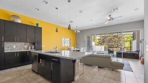 Una cocina moderna con una isla central, armarios oscuros y una pared de acento amarillo brillante.