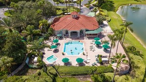 An aerial view of a resort with a central swimming pool, multiple lounge areas, and a surrounding landscaped garden. - Harry Potter Themed 3 BR (Kissimmee)