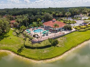 An aerial view of a resort with a swimming pool, palm trees, and a lake. - Harry Potter Themed 3 BR (Kissimmee)