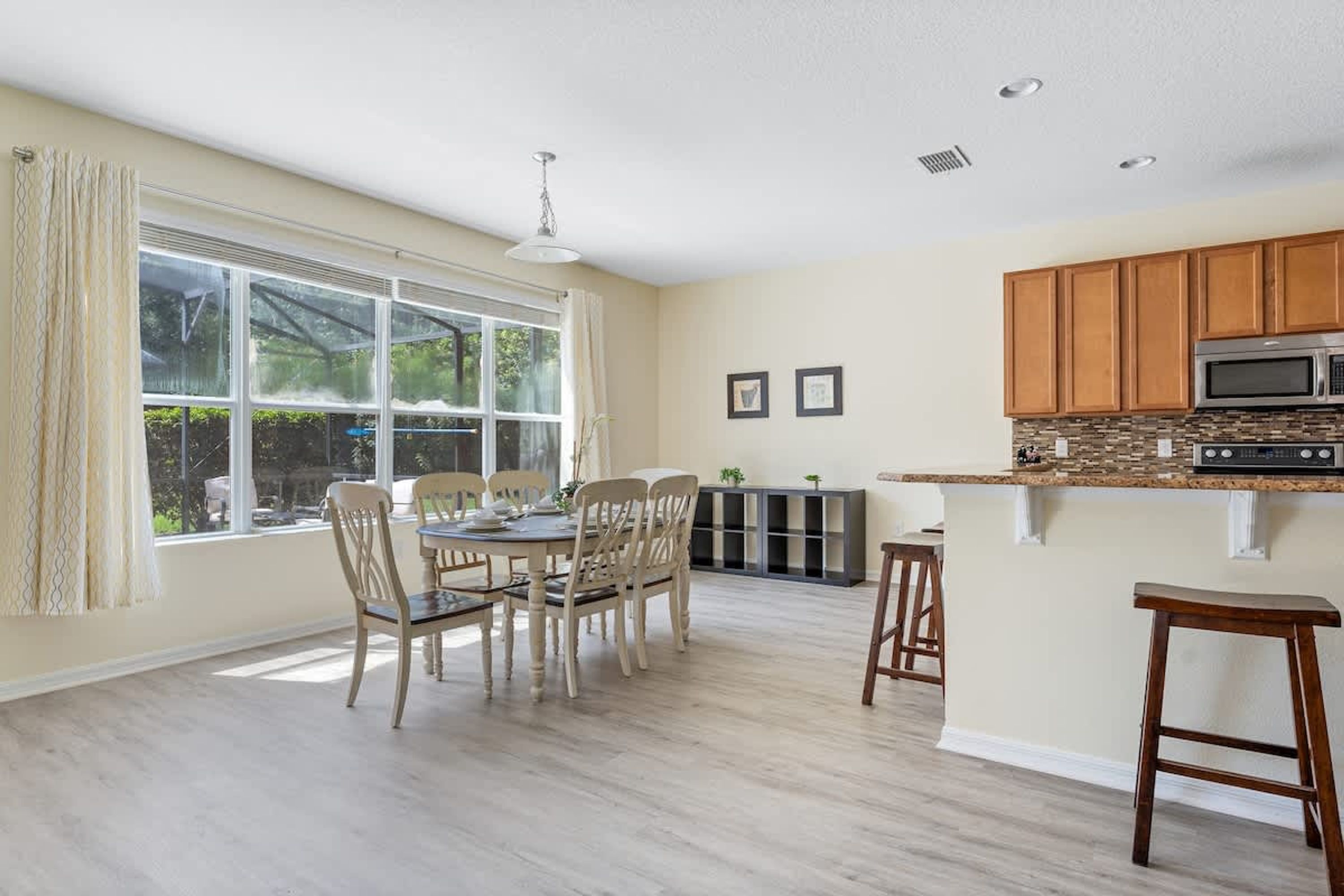 A spacious kitchen with wooden cabinets, a microwave, and a dining area with a table and chairs.