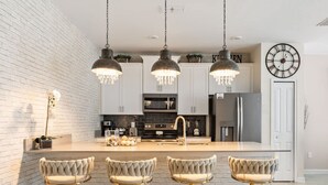A modern kitchen with a central island, pendant lighting, and bar stools.