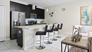 A modern kitchen with dark cabinets, stainless steel appliances, and a white island with bar stools.