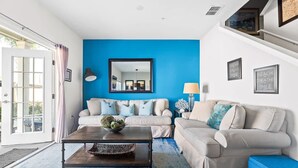 A living room with a blue accent wall, two sofas, a coffee table, and a large mirror. - Modern Decor at West Lucaya 4 BR Wl8989 (Kissimmee)