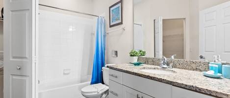 Ein Badezimmer mit Dusche, Toilette und Waschbecken mit einer Granit-Arbeitsplatte.