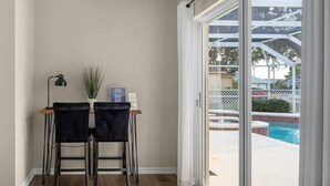 Une chambre avec vue sur la piscine, deux fauteuils, une lampe et une petite table avec une plante.