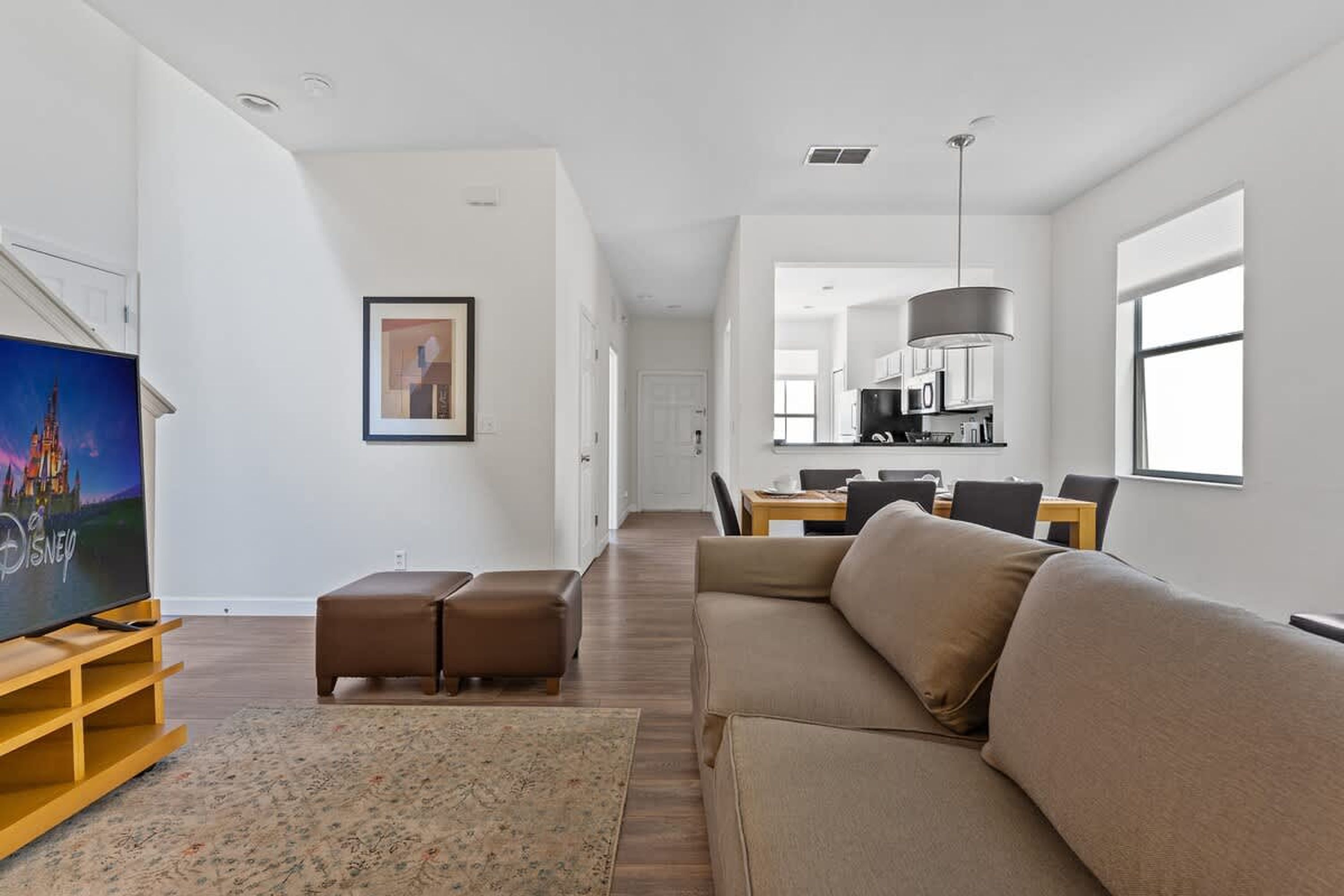 A modern living room with a sectional sofa, a flat-screen TV, and a dining area with a table and chairs.