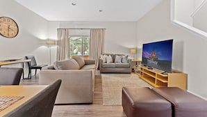 A modern living room with a sofa, a TV, and a dining area.