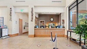 A reception area with a wooden reception desk, a clock, and a blue rope barrier.
